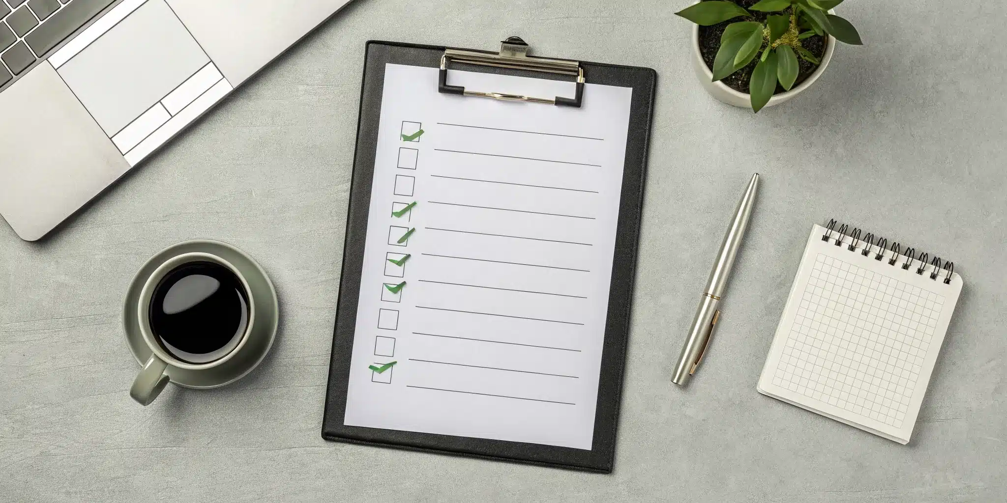 A checklist of permit renewal requirements on a clipboard with a pen and laptop.